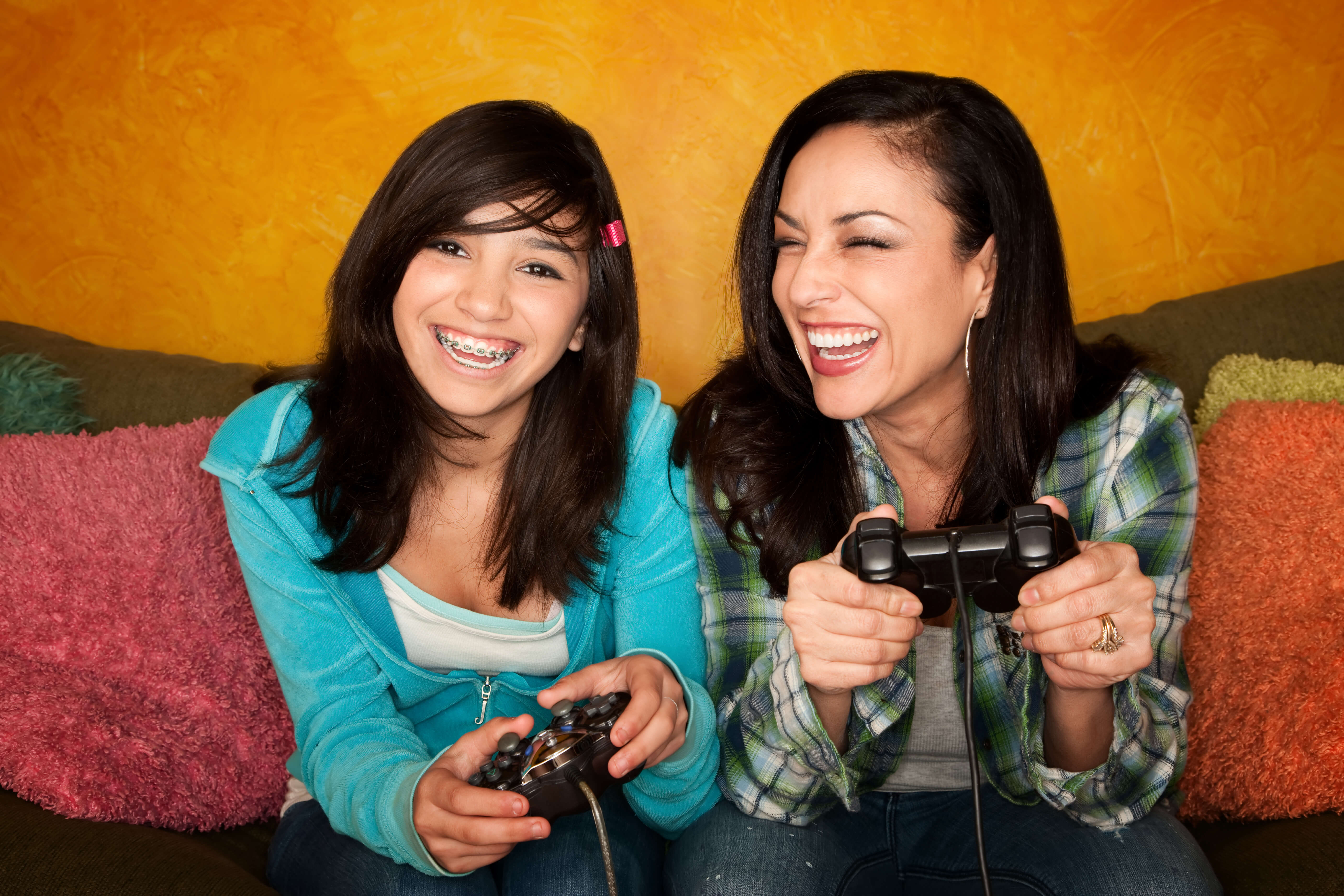 Attractive Hispanic Woman and Girl Playing a Video Game with Handheld Controllers